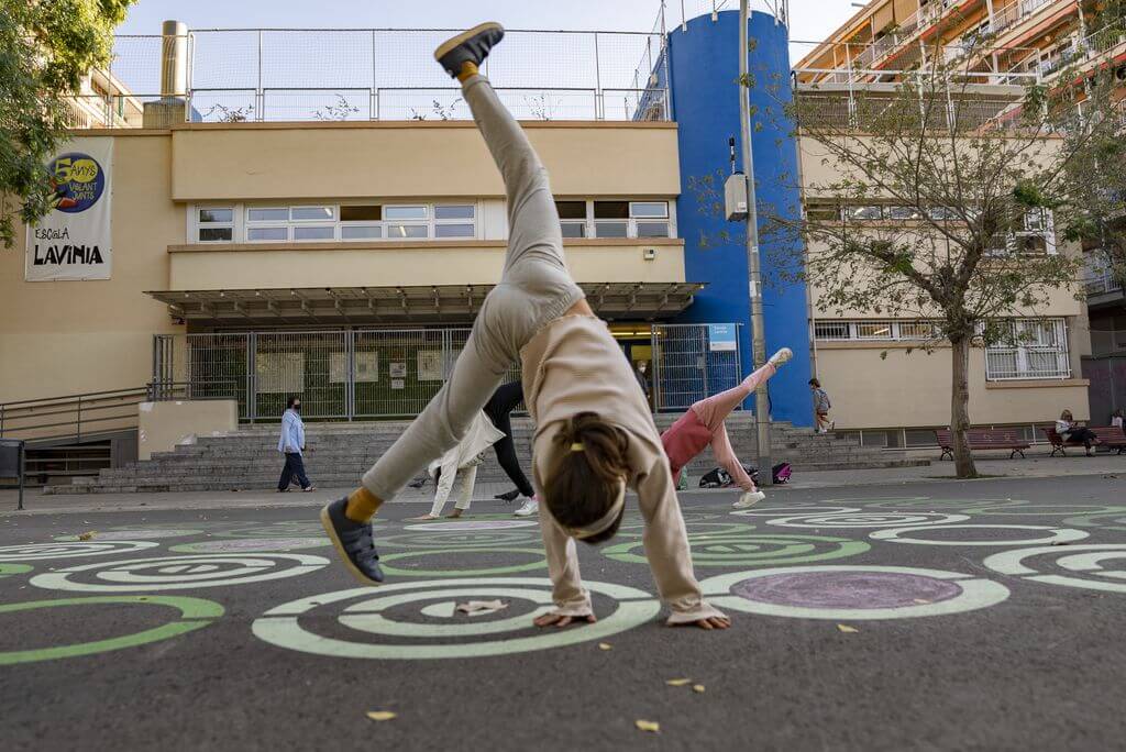 Una nena juga fent tombarelles a la zona pacificada del carrer davant de l'Escola Lavínia. <span>Àlex Losada</span>